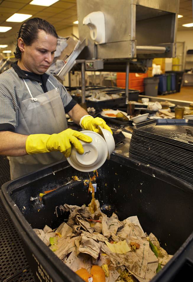 Nick Alas scrapes food waste into a bin at a Bellagio kitchen, one of many items sorted there as part of their recycling efforts Tuesday, Dec. 17, 2013.