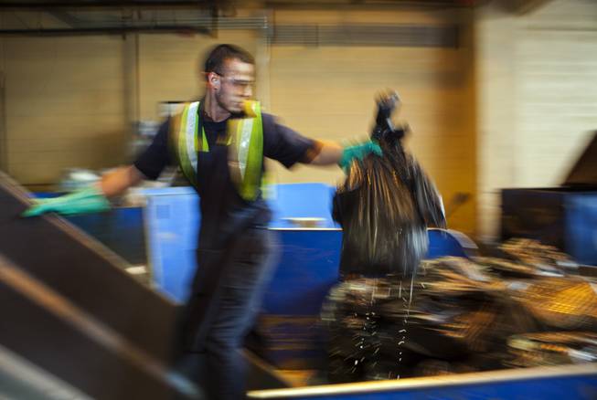 Maros Miranda tosses bags of refuse onto a sorting table at the Bellagio loading dock as they pull out certain materials for recycling and reuse Tuesday, Dec. 17, 2013.