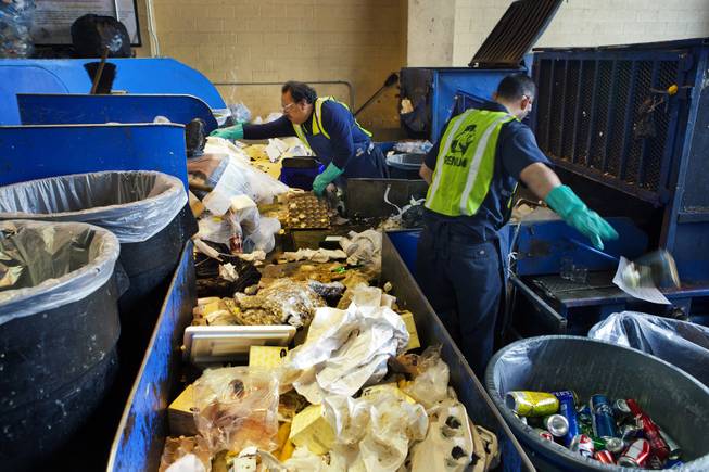 (From left) Vinnie Ramirez and Maros Miranda sort through refuse on a table at the Bellagio loading dock selecting certain materials for recycling and reuse Tuesday, Dec. 17, 2013.