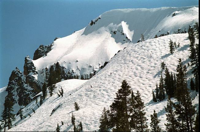 Two skiers take on a mogul field below the towering cornices of Emigrant Peak at Squaw Valley in Truckee, Calif.