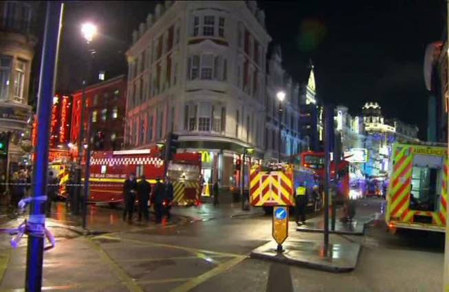 This image taken from television shows emergency services attending an incident at the Apollo Theatre, illuminated at rear right, in London's Shaftesbury Avenue, Thursday evening, Dec. 19, 2013, during a performance at the height of the Christmas season, with police saying there were "a number" of casualties. 