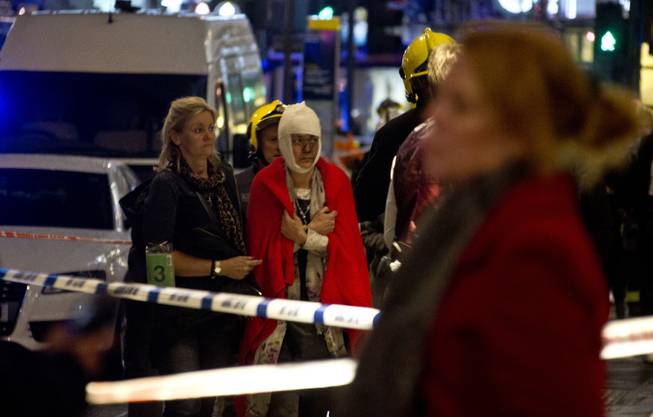 A woman stands bandaged and wearing a blanket  given by emergency services  following an incident at the Apollo Theatre, in London's Shaftesbury Avenue, Thursday evening, Dec. 19, 2013, during a performance at the height of the Christmas season, with police saying there were "a number" of casualties.