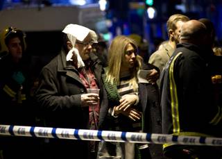 A  bandaged man comforts a woman  following an incident at the Apollo Theatre, in London's Shaftesbury Avenue, Thursday evening, Dec. 19, 2013, during a performance , with police saying there were 