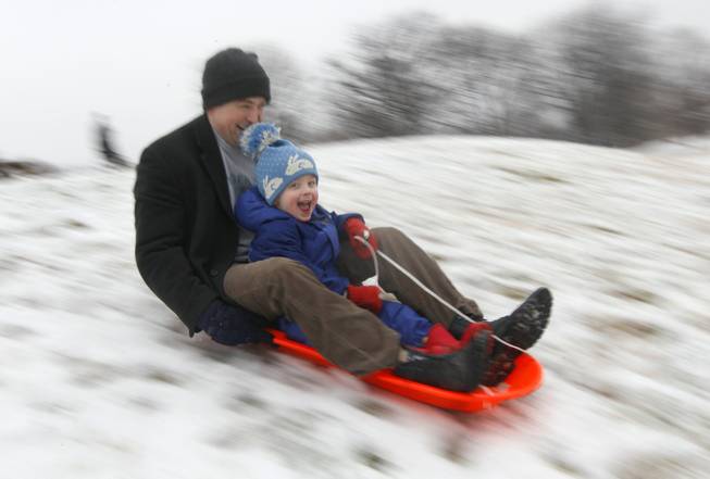 In this Saturday, Jan. 21, 2012, photo, Matt Redmond, 3, and his father, Mike, ride a sled down a hill after an overnight snowfall in Baltimore. According to a government survey released this week, the detached dad is mostly a myth. 