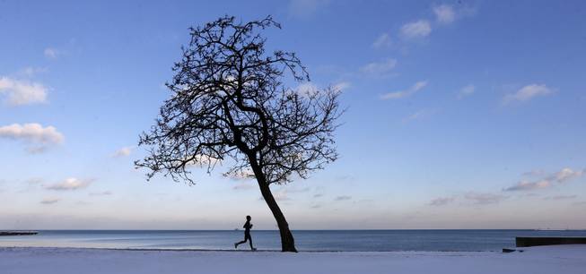 A lone runner traverses the bike and running path along Lake Michigan at the North Avenue beach as temperatures hover around freezing Tuesday, Dec. 17, 2013, in Chicago. 