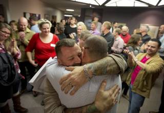 Chris Serrano, left, and Clifton Webb embrace after being married, as people wait in line to get licenses outside of the marriage division of the Salt Lake County Clerk's Office in Salt Lake City, Friday, Dec. 20, 2013. A federal judge ruled on Friday that Utah's ban on same-sex marriage is unconstitutional. (AP Photo/Kim Raff)