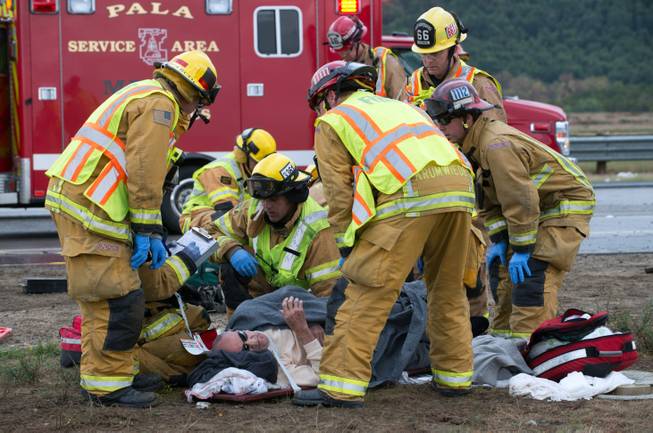 Firefighters and paramedics tend to a victim after a tour bus heading to a casino overturned on rain-slick Interstate 15 near Fallbrook, Calif., in San Diego County Thursday afternoon, Dec. 19, 2013.