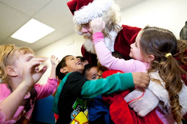 Camryn Fedderson, from right, Sergio Santos and Kaylee Murill rush into the arms of Santa Claus as he makes his arrival during the Christmas feast and holiday party provided by Siegfried and Roy at the Boys and Girls Club at 2801 E. Stewart Avenue in Las Vegas December 20, 2013.