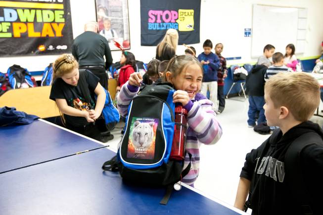 Mariana Vasquez, 7, giggles with Christopher Girlinghouse, 8, (right) after receiving a backpack filled with presents provided by Siegfried and Roy during the holiday party at the Boys and Girls Club at 2801 E. Stewart Avenue in Las Vegas December 20, 2013.