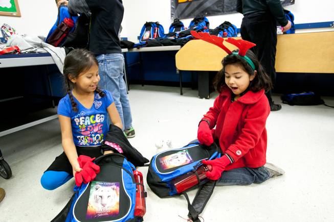 After finding red gloves in their backpacks, Yoremy Santos, 8, and Elena Davilla, 7, (left) holler with excitement as they discover more gifts provided by Siegfried and Roy during the holiday party at the Boys and Girls Club at 2801 E. Stewart Avenue in Las Vegas December 20, 2013.