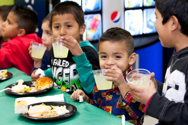 Sergio Santos, 6, (from left), Julian Lopez, 5, and Juan Martinez, 6, celebrate after expressing, "It's like a restaurant," during the Christmas feast and holiday party provided by Siegfried and Roy at the Boys and Girls Club at 2801 E. Stewart Avenue in Las Vegas December 20, 2013.