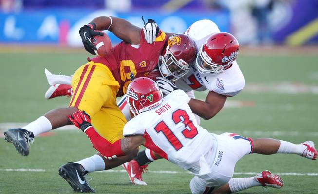 USC tight end Xavier Grimble is tackled by Fresno State safety Derron Smith and linebacker Kyrie Wilson during the Royal Purple Las Vegas Bowl Saturday, Dec. 21, 2013 at Sam Boyd Stadium. USC won the game 45-20.