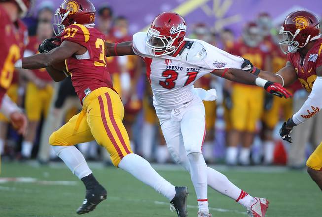 USC tight end Xavier Grimble holds the jersey of Fresno State linebacker Ejiro Ederaine as he tries to tackle USC tailback Javorius Allen during the Royal Purple Las Vegas Bowl Saturday, Dec. 21, 2013 at Sam Boyd Stadium. USC won the game 45-20.