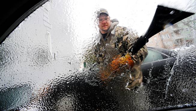 Charles Winslow clears ice off his car in Lewiston, Maine, on Sunday, Dec. 22, 2013. Ice build-up on tree limbs brought down power lines in northern New England, leaving thousands of homes and business in Vermont and Maine without electricity. 