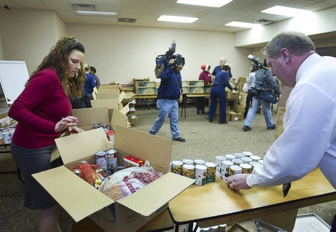 Arizona Charlie's employees Justene Thomas, director of hotel operations, and Russ Terbeek, director of casino operations, pack holiday food boxes at the Boulder Highway location Monday, Dec. 23, 2013. Casino patrons contributed loyalty card points to the Feed a Family program and bought holiday dinners for 60 families. The food baskets will be picked up by the Southern Nevada Regional Housing Authority for distribution to needy families.