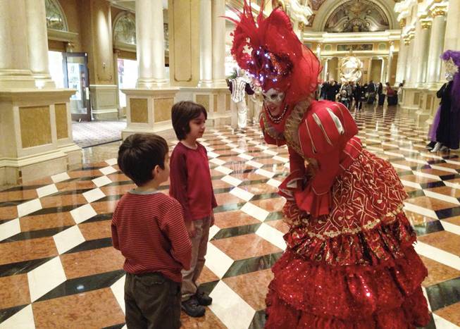 In this Thursday Dec. 5, 2013, photo, brothers Sebastian, center and Joaquin, left, visit with the Red Queen during the third-annual Winter in Venice event at the Venetian hotel-casino on the Las Vegas Strip. The Venetian is advertising the event as a public gift. Las Vegas casinos have begun staging elaborate Christmas installations in recent years to attract tourists during the slow winter months.