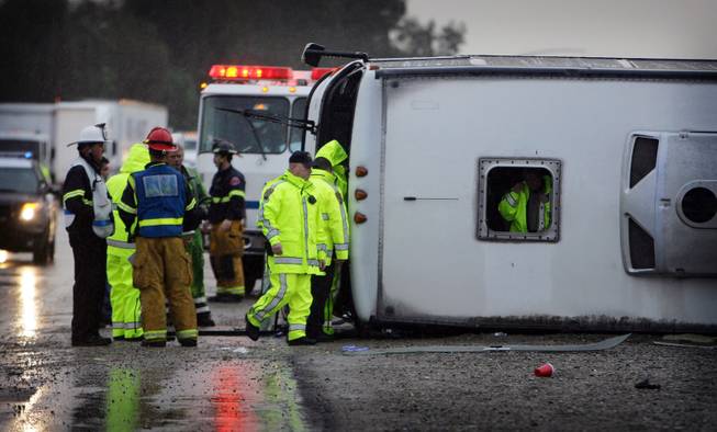 Emergency crews examine the scene of a tour bus that crashed and overturned on northbound Interstate 15 near Magnolia, on Thursday, Dec. 19, 2013, in Corona, Calif. 