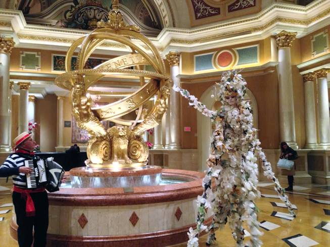 In this Thursday Dec. 5, 2013, photo, an accordion player, left, serenades a stilt walker during the third-annual Winter in Venice event at the Venetian hotel-casino.