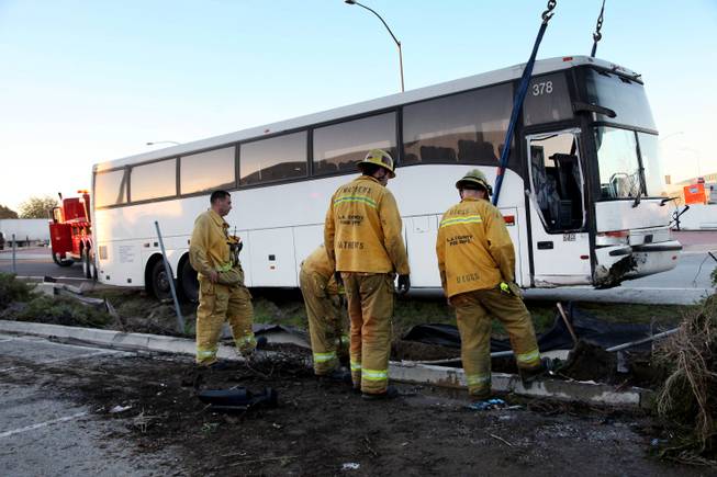 Firefighters help as a tour bus is towed out of a drainage ditch after the bus went off the shoulder of an Interstate 10 off-ramp in Baldwin Park, Calif. on Monday Dec. 23, 2013.
