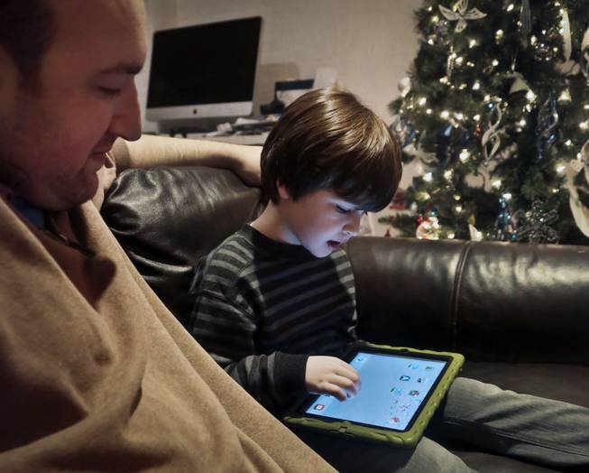 In this Dec. 3, 2013, photo, Adam Cohen watches as his son Marc, 5, uses a tablet at their home in New York. Tablets of all types are expected to rank among the top holiday gifts for children this year, but some experts and advocates question the educational or developmental benefits for youngsters.