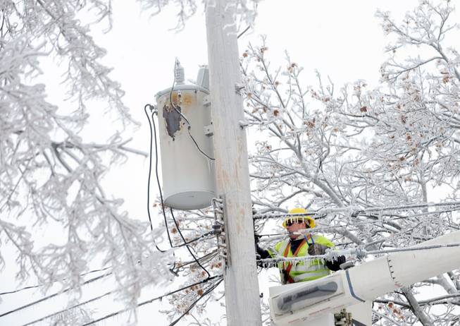 Dave Dora, a lineman from Grand Haven Board of Light and Power, works on connecting fallen wires on Macon Avenue in Lansing, Mich., Monday, Dec. 23, 2013. From Michigan to Maine, hundreds of thousands remain without power days after a massive ice storm — which one utility called the largest Christmas-week storm in its history — blacked out homes and businesses in the Great Lakes and Northeast.