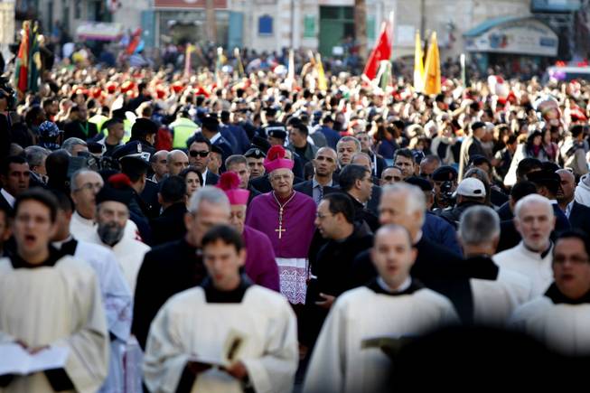 Latin Patriarch of Jerusalem Fouad Twal, center, arrives to the Church of the Nativity, traditionally believed by Christians to be the birthplace of Jesus Christ on the Christmas Eve in the West Bank town of Bethlehem, Tuesday, Dec. 24, 2013.