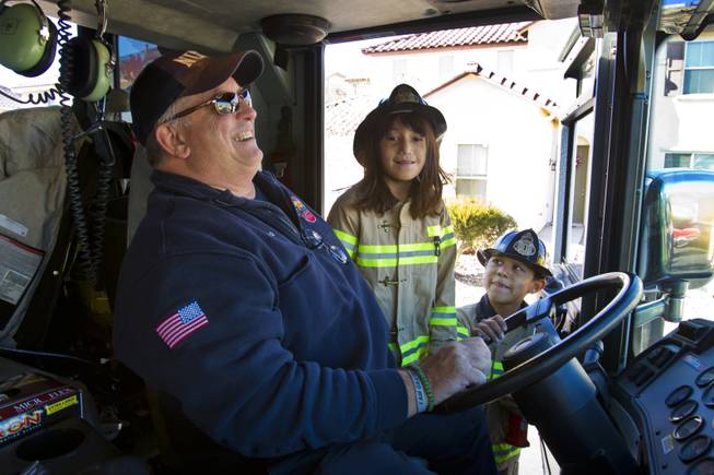 North Las Vegas Firefighter Chuck Norris is amused by Lupita Cambero, 10, and brother Isaac, 8, who convince him for a ride on Engine 57 Christmas morning Wednesday, Dec. 25, 2013.