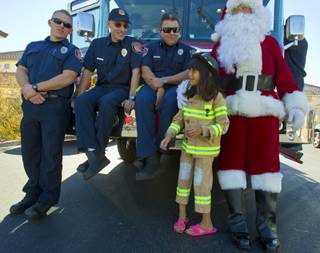 Operation FireH.E.A.T. (Holiday Emergency Assistance Team) firefighters enjoy a visit with Lupita Cambero, 10, and Santa on Christmas morning after delivering presents Wednesday, Dec. 25, 2013.