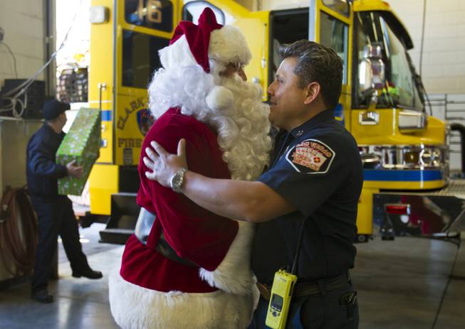 Santa greets firefighters at Las Vegas Fire Rescue Station 8 on Christmas morning Wednesday, Dec. 25, 2013, as Operation FireH.E.A.T. (Holiday Emergency Assistance Team) packs presents onto fire engines to deliver for a family that recently lost their mother in fatal fire.