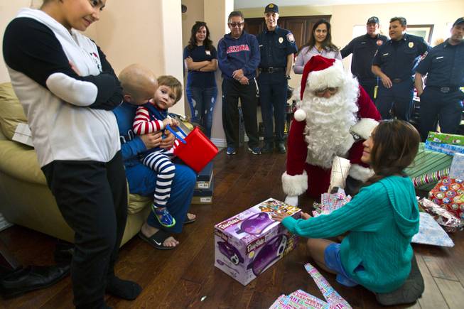 Ashley Cambero, 11, opens a present from Santa on Christmas morning as a group from Operation FireH.E.A.T. (Holiday Emergency Assistance Team) helps deliver the gifts Wednesday, Dec. 25, 2013.