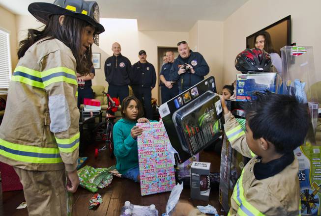 Lupita Cambero, 10, with siblings Ashley, 11, and Isaac, 8, open presents on Christmas morning brought to them from Operation FireH.E.A.T. (Holiday Emergency Assistance Team) on Wednesday, Dec. 25, 2013.