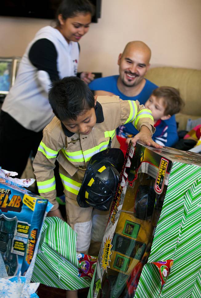 Isaac Cambero, 8, opens a present on Christmas morning brought to his family from Operation FireH.E.A.T. (Holiday Emergency Assistance Team) on Wednesday, Dec. 25, 2013.