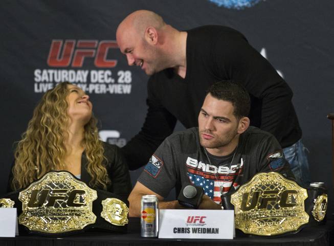 Ronda Rousey chats briefly with Dana White as Chris Weidman considers a reporter's question during a press conference for the upcoming UFC168 at the MGM Grand Hotel & Casino with commentary from the top fighters on the card Thursday, Dec. 26, 2013.
