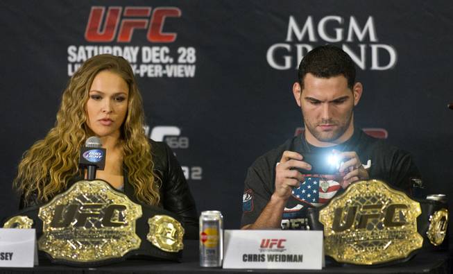 Ronda Rousey considers her answer as Chris Weidman takes a photo during a press conference for the upcoming UFC168 at the MGM Grand Hotel & Casino with commentary from the top fighters on the card Thursday, Dec. 26, 2013.