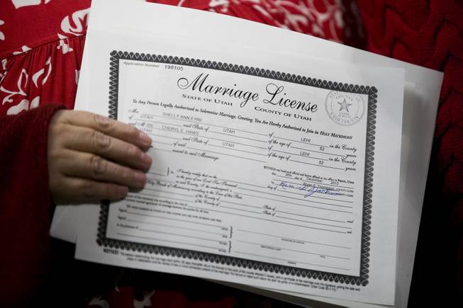 In this photo taken on Thursday, Dec. 26, 2013, Shelly Eyre, left, holds the marriage license just issued to her and her partner Cheryl Haws at the Utah County Clerk's office in Provo, Utah. 