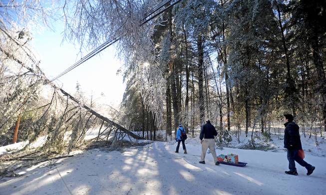 Chris Devine hauls a sled of gifts with his daughter Jordan, 11, and stepson Derek Gervais, 20, to their home in Belgrade, Maine, on Wednesday, Dec. 25, 2013. The Devines lost power Monday and have hauled their supplies via sled ever since. Trees and power lines are down in their driveway.
