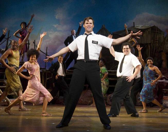 In this theater publicity image released by Boneau/Bryan-Brown, Andrew Rannells, center, performs with an ensemble cast in "The Book of Mormon" at Eugene O'Neill Theater in New York.