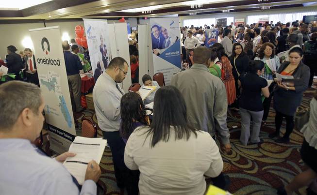This Aug. 14, 2013, file photo shows job seekers checking out companies at a job fair in Miami Lakes, Fla. More than 1 million Americans are bracing for a harrowing, post-Christmas jolt as federal unemployment benefits come to a sudden halt this weekend. 