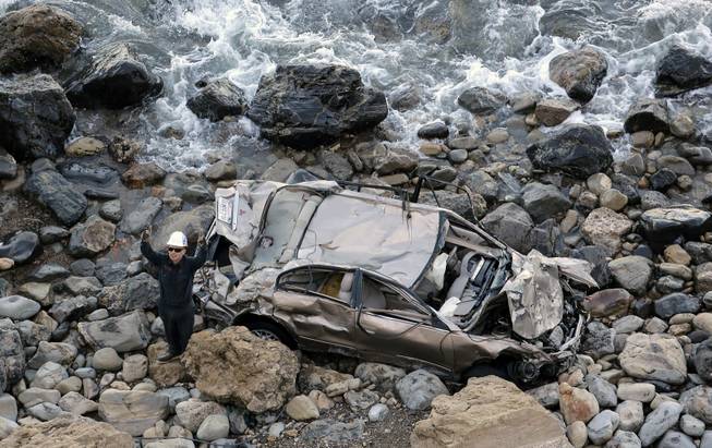 A towing company worker prepares to pull the mangled wreckage of a car driven over a Palos Verdes Peninsula cliff by a 19-year-old Los Angeles man on Friday, Dec. 27, 2013, in Palos Verdes Estates, Calif. 