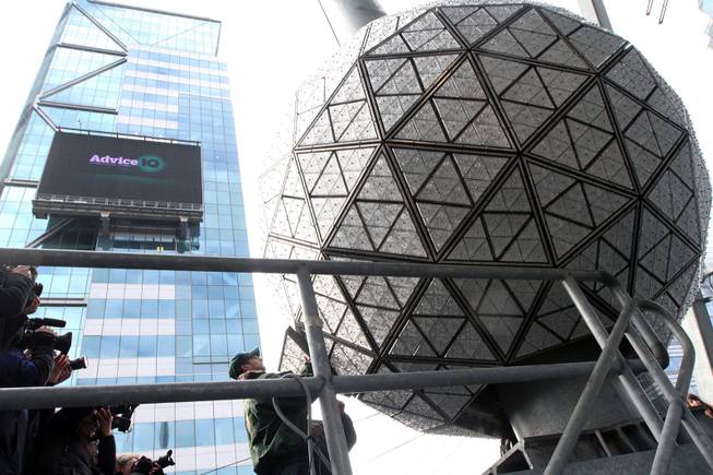With members of the media gathered, at left, a Waterford crystal triangle is installed on the New Year's Eve Ball by Landmark Signs workers, right, Friday, Dec. 27, 2013 on the roof of One Times Square in New York. 