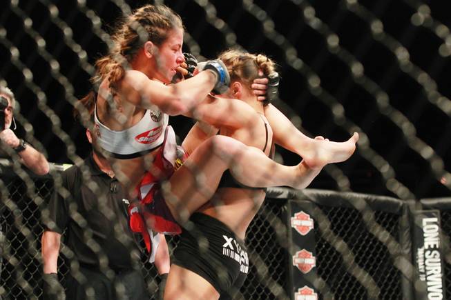 Miesha Tate leaps on Ronda Rousey during their fight at UFC 168 Saturday, Dec. 28, 2013 at the MGM Grand Garden Arena. Rousey won via tap out with an arm bar.
