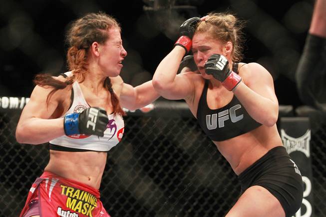 Miesha Tate hits Ronda Rousey with a left during their fight at UFC 168 Saturday, Dec. 28, 2013 at the MGM Grand Garden Arena. Rousey won via tap out with an arm bar.