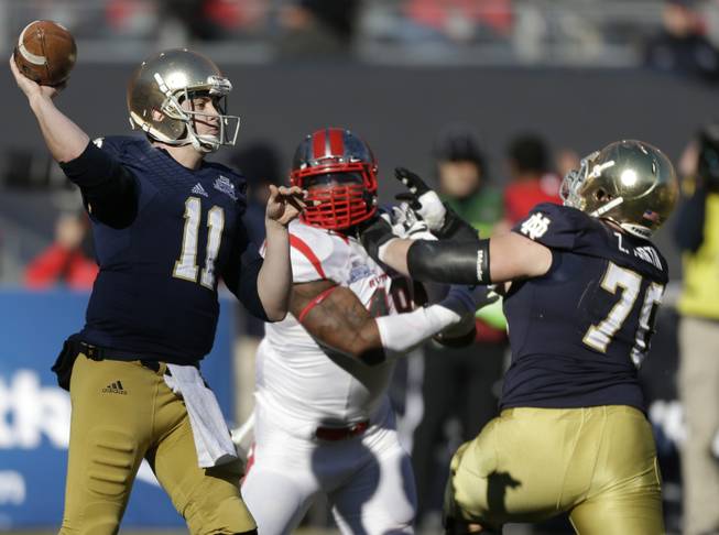 Notre Dame quarterback Tommy Rees throws a pass as lineman Mark Harrell blocks Rutgers' Marcus Thompson during the first half of the Pinstripe Bowl NCAA college football game Saturday, Dec. 28, 2013, at Yankee Stadium in New York. 
