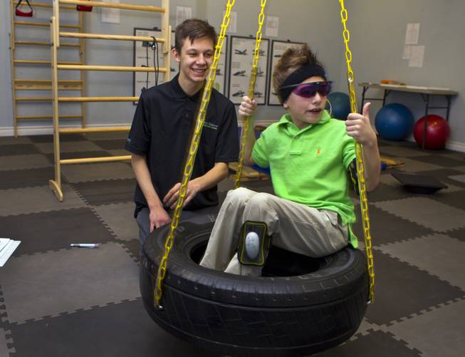 Sensory motor coach Cody Furin spins the tire swing for Christian Culotta, 9, as they work on physical and emotional stability at the Brain Balance Achievement Center on Monday, Dec. 30, 2013.