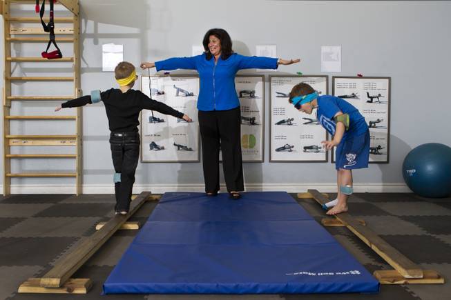 Dr. Susan DeVito coaches Chase Black, 7, and Cash Johnson, 7, on the balance beam within the Brain Balance Achievement Center on Monday, Dec. 30, 2013.