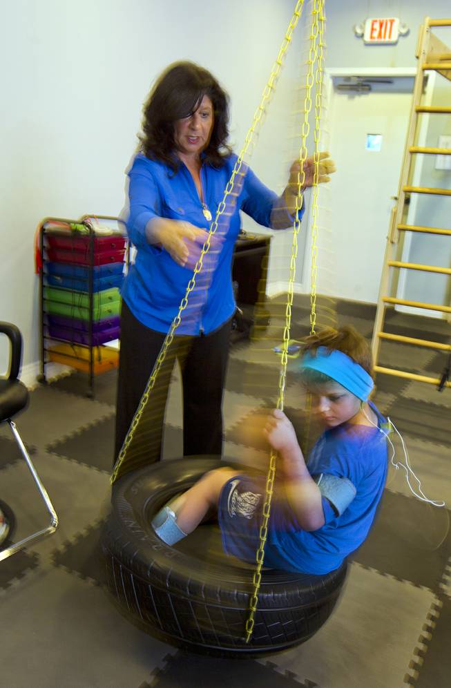 Dr. Susan DeVito spins Cash Johnson, 7, on the tire swing for physical and emotional stability within the Brain Balance Achievement Center on Monday, Dec. 30, 2013.