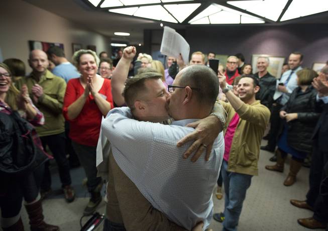 In this Friday, Dec. 20, 2013 file photo, Chris Serrano, left, and Clifton Webb kiss after being married, as people wait in line to get licenses outside of the marriage division of the Salt Lake County Clerk's Office in Salt Lake City. 