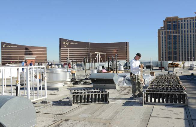 In this photo provided by the Las Vegas News Bureau, a technician from Fireworks by Grucci makes preparations atop  of the Treasure Island hotel for the Las Vegas New Years Eve pyrotechnic extravaganza, Monday, Dec. 30, 2013 in Las Vegas, Nev. The program will launch more than 80,000 effects from the MGM Grand, Aria, Planet Hollywood, Caesars Palace, Treasure Island, The Venetian and Stratosphere. (Photo/Las Vegas News Bureau, Darrin Bush)