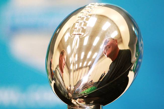 UNLV head coach Bobby Hauck, left, and North Texas head coach Dan McCarney are reflected in the Heart of Dallas Bowl trophy during a news conference Tuesday, Dec. 31, 2013 at the Cotton Bowl in Dallas.