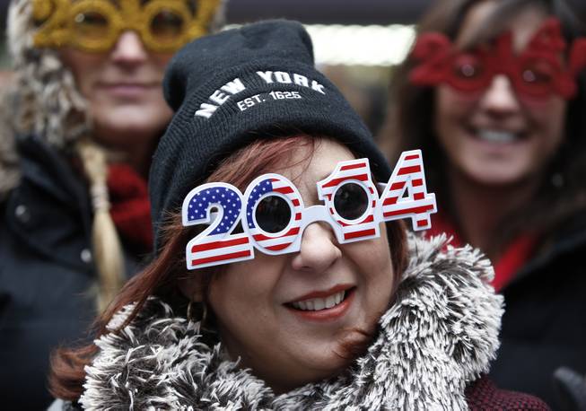Carmen Glavan, of Monterrey, Mexico, wears 2014 glasses with an American theme as she and others wait in Times Square for the midnight ball drop on New Year's Eve, Tuesday, Dec. 31, 2013, in New York. The crowds will have to wait more than ten hours for the ball drop.